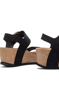 Sandali con zeppa in suede nero, tacco in sughero, con schienale aperto e design a fasce. Presentano una base in sughero testurizzato e suola in gomma per una buona aderenza.