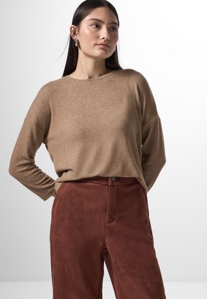 Maglione marrone a maniche lunghe in tessuto morbido con una vestibilità rilassata, abbinato a pantaloni in suede color ruggine con bottone frontale e tasche.