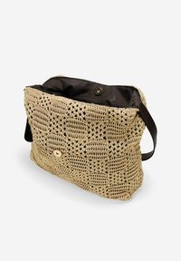 Bolso de tote de ganchillo en rafia natural con un acabado texturizado, forro de tela oscura, cierre de botón dorado y correa de hombro negra.