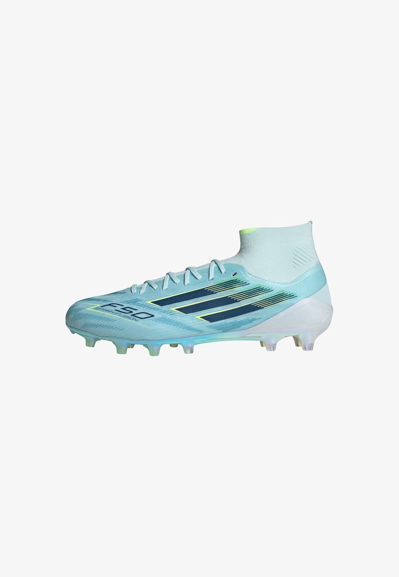 Chaussure de football montante bleu clair avec des rayures noires, des lacets blancs et des crampons moulés sur la semelle pour terrain ferme.