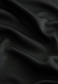 Tissu noir lisse avec des plis doux et une texture tissée subtile créant des ombres et des reflets délicats.