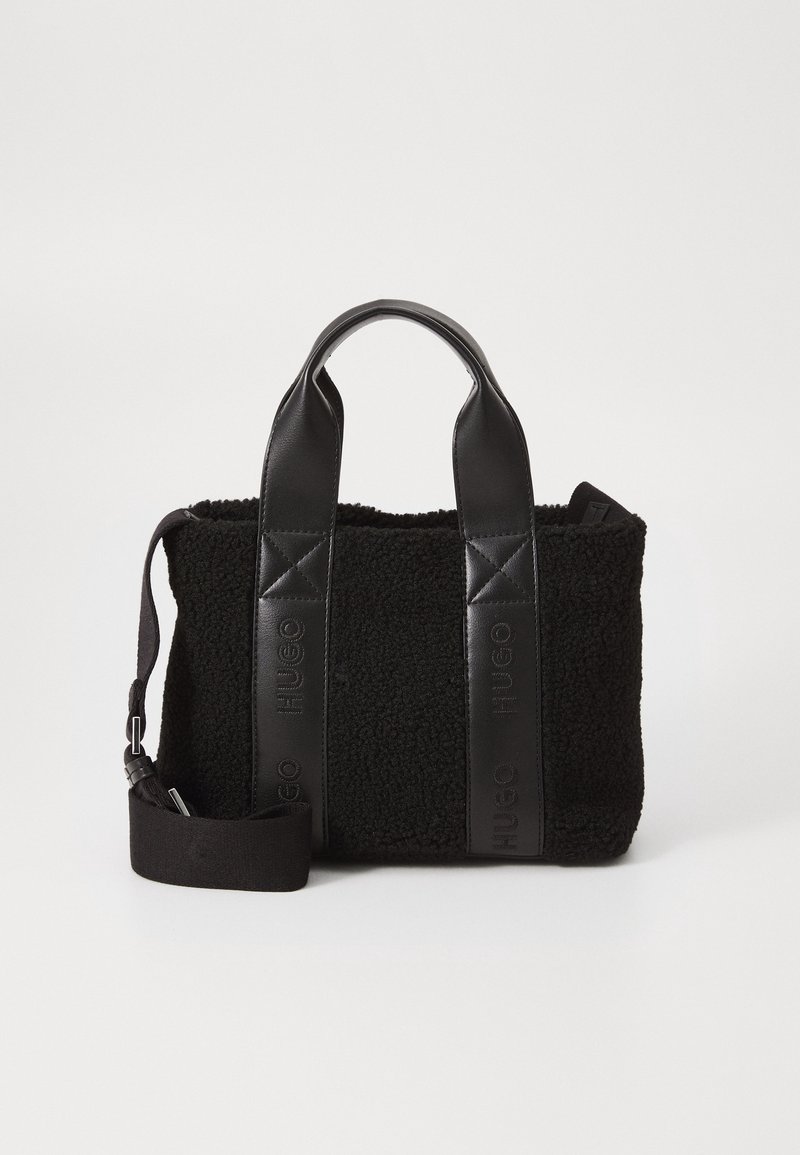 Sac tote noir texturé avec poignées en cuir et bandoulière ajustable, avec un logo embossé "HUGO" sur les panneaux en cuir.