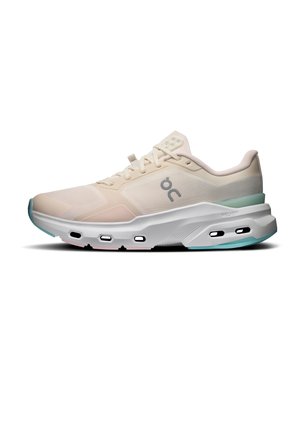 Beige athletic sneaker with white sole, light green heel, lace-up closure, mesh upper, and black oval vents along the midsole.