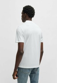 White short-sleeve t-shirt made of smooth cotton, featuring a simple design with a slight crew neck and a relaxed fit.