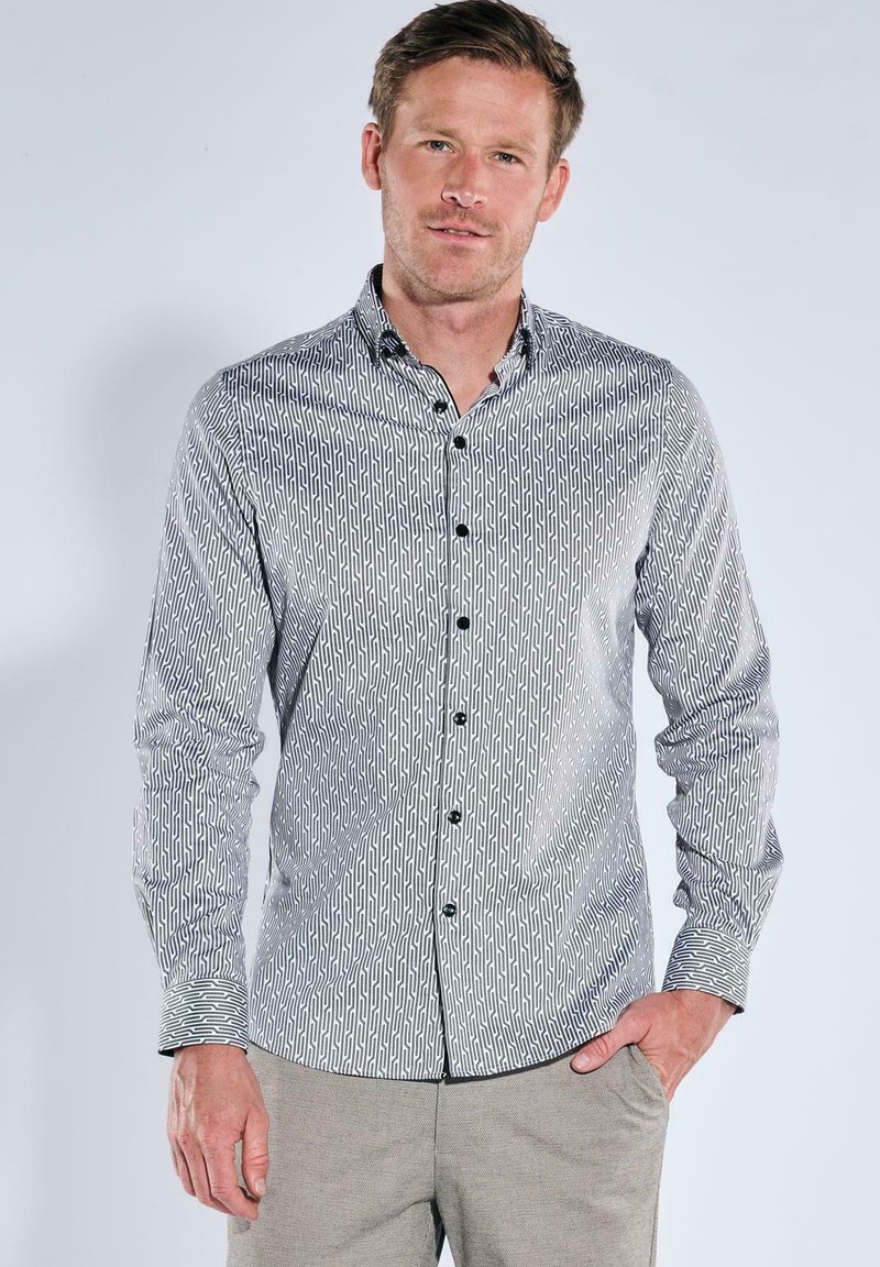 Hemd mit Knopfleiste in einem schwarz-weißen geometrischen Muster, langen Ärmeln und klassischem Kragen, kombiniert mit einer glatten Textur.