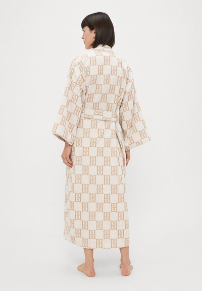 Pikk kreemivärvi hommikumantel, millel on korduv beež geomeetriline muster. Omab rihmaga talje ja laiad varrukad. Pehme kangastekstuuri.