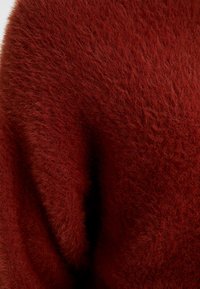 Rode, pluizige brei-stof met een zachte textuur en een dichte, fuzzy uitstraling. De kleur is een diepe, rijke rood.