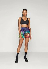 Μαύρο αθλητικό σουτιέν συνδυασμένο με πολύχρωμα, σχεδιασμένα σορτς που διαθέτουν συνδυασμό πράσινου, μωβ και καρό σχέδια. Περιλαμβάνει μαύρες αθλητικές κάλτσες και παπούτσια.