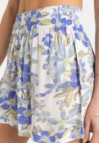 Bloemendruk rok met een witte achtergrond, blauwe en gele bloemen, elastische tailleband en lichte, gestructureerde stof.