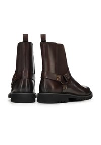 Bottes basses en cuir marron avec un design élégant, des panneaux latéraux élastiques, des accents de boucle et une semelle en caoutchouc noire durable.
