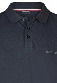Navy Polo-Shirt aus strukturiertem Stoff mit einer Knopfleiste mit drei Knöpfen, gesticktem Logo und kontrastierenden Kragenakzenten in Rot und Weiß.