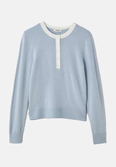 Ljusblå stickad tröja med en rund, vit rundhalsade krage, knappslå och ribbade mudd och nederkant. Mjuk textur, avslappnad passform.