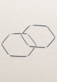 Sechseckige Creolen aus poliertem Silbermetall, mit glatten Kanten und geometrischem Design. Leicht und mit glänzender Oberfläche.