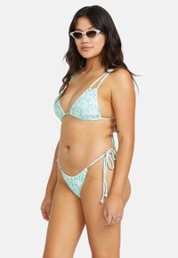 Bikini bleu clair avec un motif floral, des fines bretelles, un haut triangulaire et des liens ajustables en bas. Texture lisse dans l'ensemble.