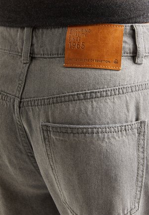 Grijze denim jeans met een gestructureerd oppervlak, voorzien van een leren label met de tekst "BLIJF KERNWAARDEN SINDS 1965" van United Colors of Benetton.