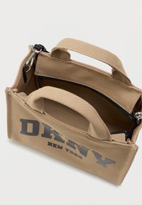 Beige vászontáska dupla fogantyúkkal, cipzáras zsebbel és fekete akcentusokkal. A táska oldalán kiemelkedő "DANNY NEW YORK" felirat található.