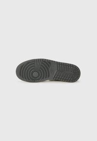Nike spordijalatsite tald mustast kummist, millel on ringikujulised ja sirged mustrid, sujuva tekstuuriga viimistlus ning logo detail.