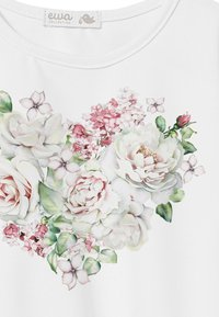 Biała koszula z krótkim rękawem z nadrukiem w kwiaty, z różowymi i białymi różami, delikatnymi liśćmi oraz mniejszymi kwiatami w stonowanych odcieniach.
