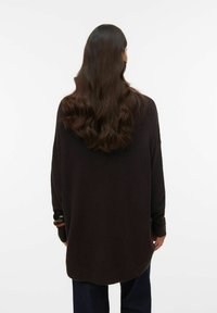 Overdimensioneret, langærmet sweater i mørkebrun, med ribstrikkede manchetter og en rund nederkant, lavet af blødt strikket stof.