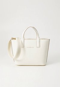 White tote bag made of faux leather, featuring two short handles, a detachable shoulder strap, and embossed brand logo on the front.