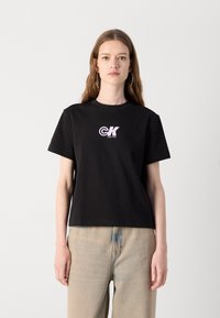 Zwarte katoenen T-shirt met korte mouwen, voorzien van een roze en witte CK-logo op de borst. Eenvoudig, relaxed-fit ontwerp.