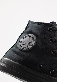 Sorte kanvas høyhælte sneakers med rund gummisåle og signatur Converse All Star logo-patch. Inkluderer svarte lufthull og stikningsdetaljer.