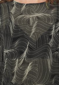 Tecido preto translúcido com linhas e padrões brancos ondulados. A textura parece suave, com sutis brilhos ao longo de toda a superfície.