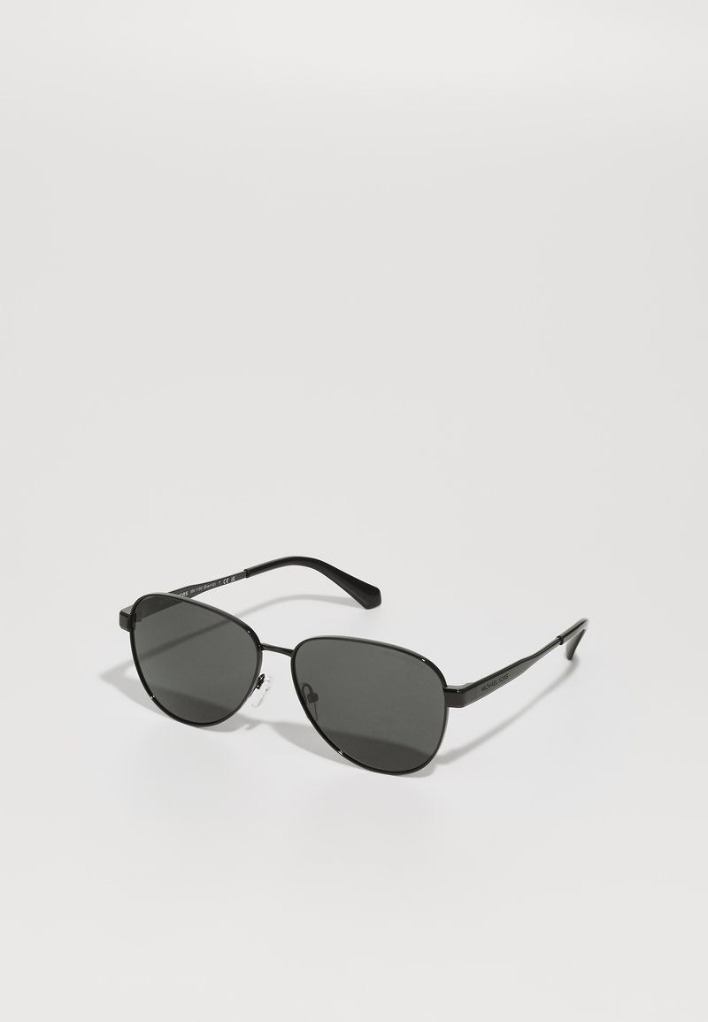 Lunettes de soleil avec monture noire en métal et verres gris, présentant une forme ovale, des branches fines et des plaquettes de nez ajustables. Design minimaliste.