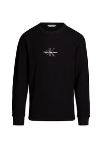 Černé triko s dlouhými rukávy vyrobené z texturované pleteniny. Na přední straně se nachází bílé logo "Calvin Klein Jeans" a výrazný monogram "CK".