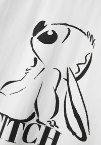 Camiseta blanca con una ilustración de un conejo de dibujos animados negro, con ojos grandes y orejas largas, junto a un texto en negrita debajo del diseño.