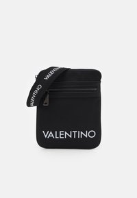 Svart nylon crossbody-väska med dragkedja, försedd med en framträdande vit "VALENTINO"-logotyp och en texturerad justerbar rem.