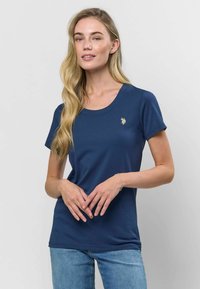 Sötétkék pamut póló kerek nyakkiv�ágással, rövid ujjakkal és egy kis hímzett arany logóval a mellrészen. Simaság jellemzi.