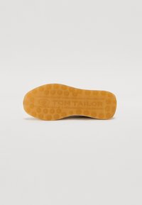 Semelle en caoutchouc brun clair avec un motif en nid d'abeille texturé et le logo "TOM TAILOR" en relief, conçue pour la traction et la durabilité.