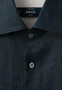 Colletto di camicia slim fit grigio scuro con due bottoni allacciati, che mostra l'etichetta "Essential MNG Slim Fit" all'interno del collo.