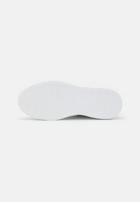 Suela de zapatilla blanca con patrones de olas texturizados, bordes lisos y sección central ligeramente elevada. Diseño minimalista, material duradero.