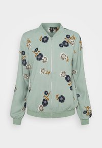 Grüne Bomberjacke aus weichem Stoff, mit floralen Mustern in Dunkelblau, Weiß und Orange, gerippten Bündchen und einem Reißverschluss.