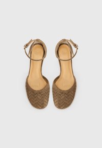 Sandales en daim tressé marron avec des brides de cheville, bouts carrés, surface texturée et talons plats. Doublure intérieure lisse et semelle extérieure ronde.