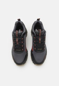 Black and gray sneakers with mesh and synthetic material, red accents, textured surface, and padded collar. Features intricate lace detailing.
