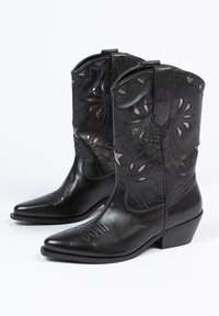 Zwarte leren cowboylaarzen met spitse neuzen, ingewikkelde uitgesneden bloemmotieven en een gestapelde hak. Gladde textuur met decoratieve stiksels.