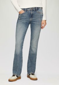 Lichtblauwe flared jeans van denim met een klassiek vijf-pocket ontwerp, voorzien van subtiele whiskering, een vervaagde textuur en riemlussen.