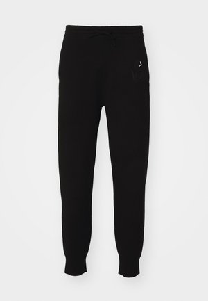 Pantaloni de trening din bumbac negri, cu talie ajustabilă prin șnur, picioare tapered și detalii brodate cu logo-ul pe partea stângă. Textură netedă.