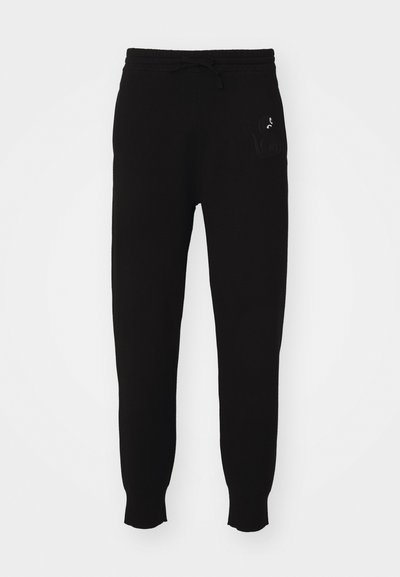 Schwarze Baumwoll-Sweatpants mit einem Kordelzugbund, schmal zulaufenden Beinen und gesticktem Logodetail auf der linken Seite. Glatte Textur.
