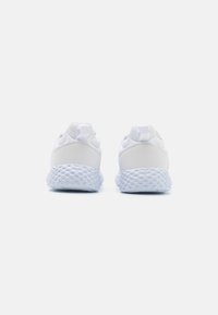 Baskets blanches avec une semelle en caoutchouc texturé, un matériau supérieur lisse et des languettes au talon pour un enfilage facile.