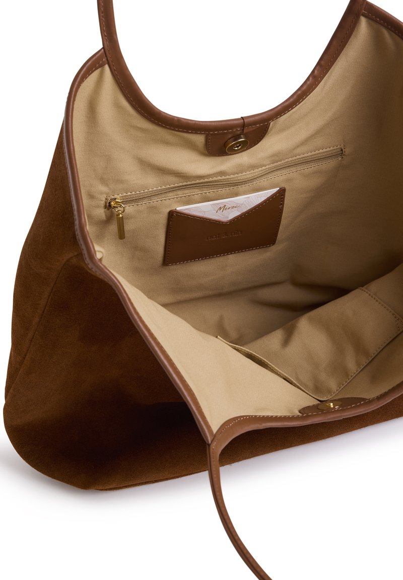 Sac cabas en suède marron avec détails en cuir. L'intérieur est doté d'une doublure beige, d'une poche zippée et d'un emplacement pour carte. Spacieux avec des bords arrondis.