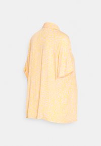 Camisa amarela de corte solto com um padrão texturizado em rosa, featuring um colarinho e mangas curtas, ideal para um uso descontraído.