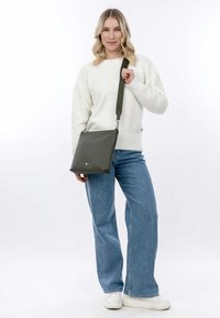 Borsa a tracolla verde sintetica dalla forma rettangolare, con tracolla regolabile e accessori in argento. Texture liscia. Design minimalista.