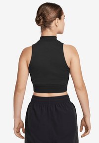 Top preto cropped sem mangas com colarinho alto e barra canelada. Tecido suave e design ajustado, combinado com calções escuros com cintura elástica.