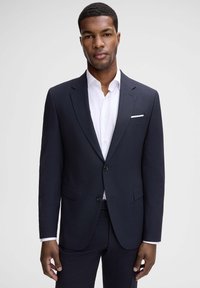 Marineblazer mit Zweiknopfverschluss, Revers mit Kerbkragen und Seitentaschen, kombiniert mit einem weißen Hemd mit Kragen. Glatte, maßgeschneiderte Passform.