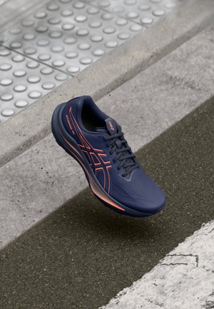 Basket de course en bleu marine avec des accents orange. Comprend un dessus texturé, un col rembourré et une semelle confortable. Design léger pour plus de confort.