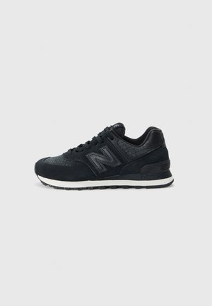 Czarny sneaker New Balance z teksturowaną cholewką, białą środkową podeszwą, czarną zewnętrzną podeszwą i sznurowanym zapięciem, pokazany z boku na jasnoszarym tle.
